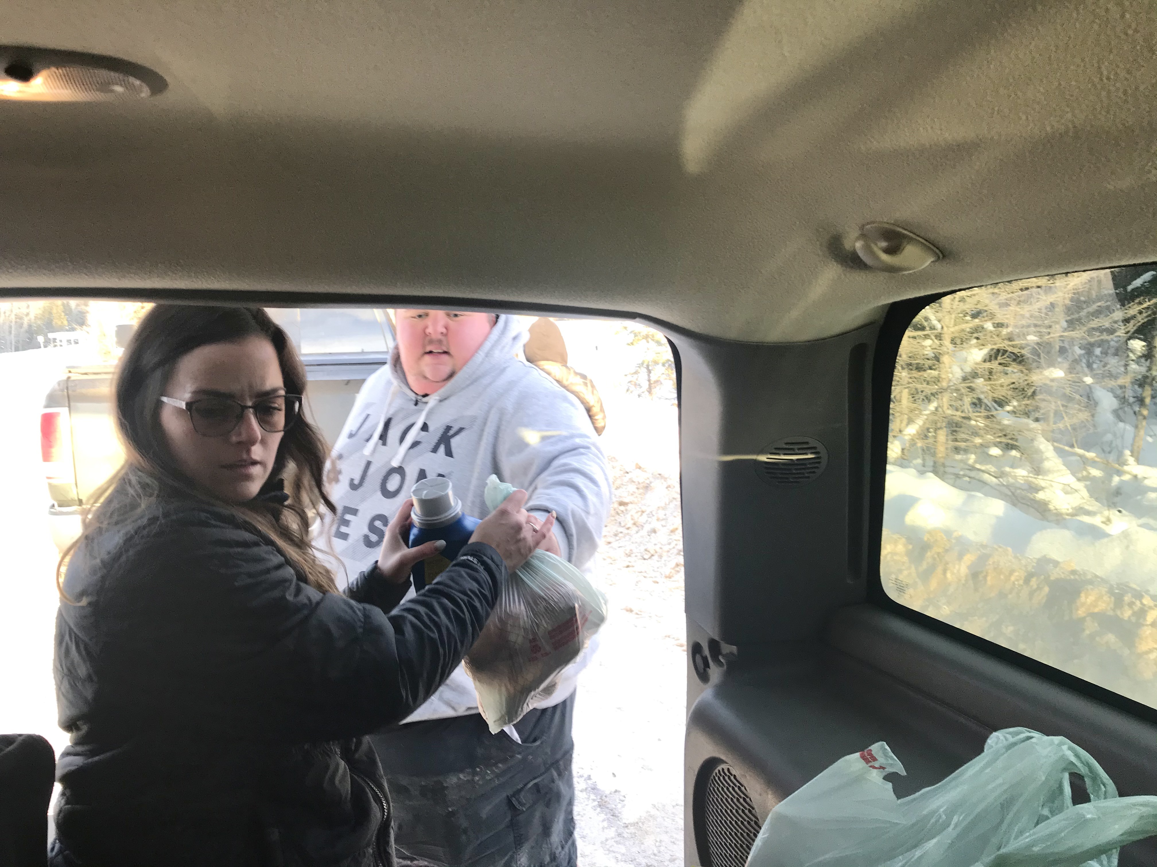 Feenstra passes plastic bags of groceries to Shank at the N.W.T.-Alberta border. (Anna Desmarais/CBC)